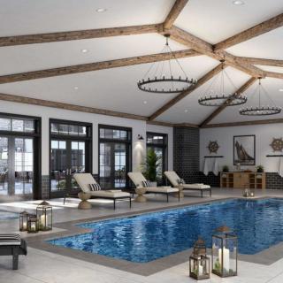 A luxurious indoor pool area with lounge chairs and elegant chandeliers, featuring wooden beam ceilings and large windows.