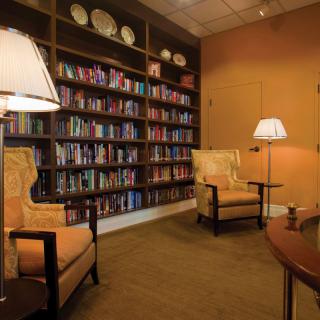 A cozy library with bookshelves, armchairs, and warm lighting.