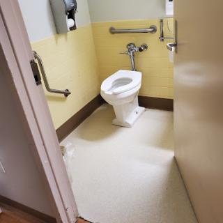 A view of an accessible bathroom featuring a toilet and safety handrails.