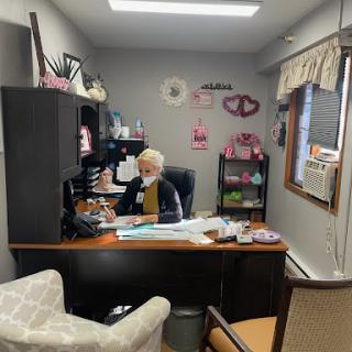 A cozy office space featuring a woman at her desk, surrounded by personal decorations.