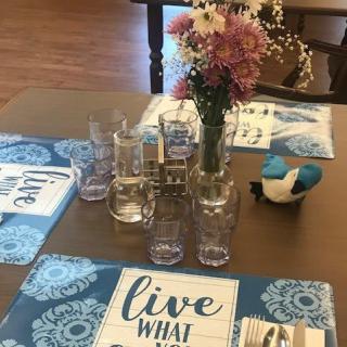 A beautifully set dining table with floral arrangements and inspirational placemats.
