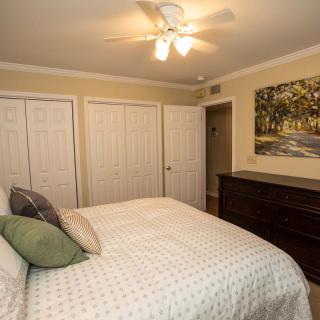 A cozy bedroom featuring a bed with pillows, a large wardrobe, and a dresser under wall art.
