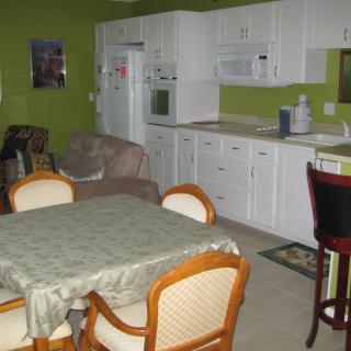 A cozy kitchen and dining area with white cabinets against green walls.