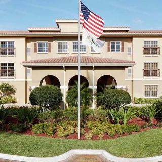 A large building with a U.S. flag in front, surrounded by well-maintained landscaping and trees.