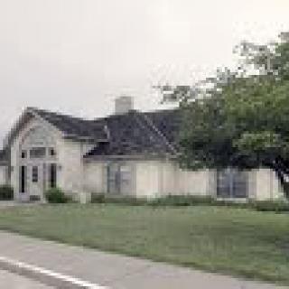 A suburban house with a lawn and trees in front.