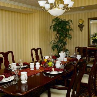 An elegant dining room featuring a formally set table with a chandelier overhead and striped wallpaper.