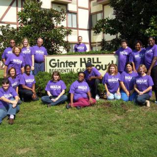 A group of people wearing purple shirts gathered in front of a sign reading 'Ginter Hall South'.