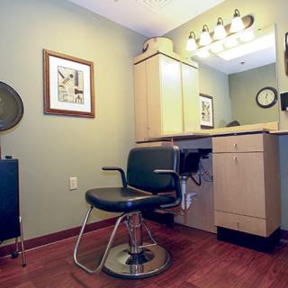 A cozy hair salon setup with a barber chair and mirror under warm vanity lights.