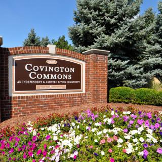 A landscaped entrance sign for Covington Commons surrounded by colorful flowers and greenery.