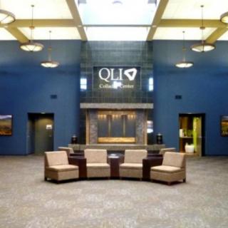 A modern lobby with a circular seating arrangement and high ceilings, featuring a reception desk in the background.