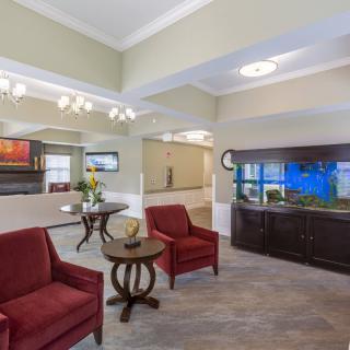 A cozy lobby area with red chairs, a table, and a large aquarium.