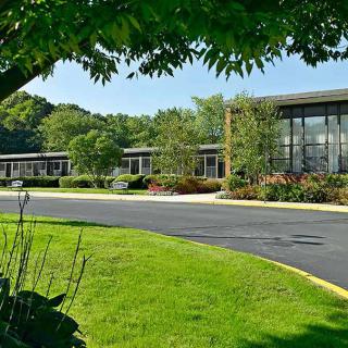 A modern office building surrounded by lush greenery and a well-maintained lawn.