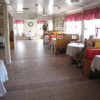 An interior view of a restaurant with tables, booths, and red curtains by the windows.