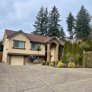 A charming residential house surrounded by trees and well-maintained landscaping.