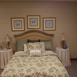 A cozy and elegantly decorated bedroom with a floral bedspread, two vintage lamps, and framed artwork above the headboard.