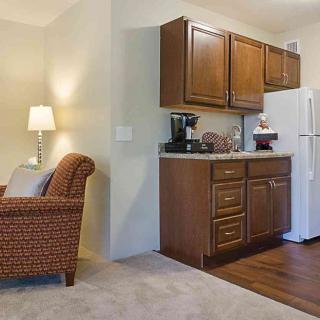 A cozy living space with a compact kitchen area featuring wooden cabinets and a refrigerator.