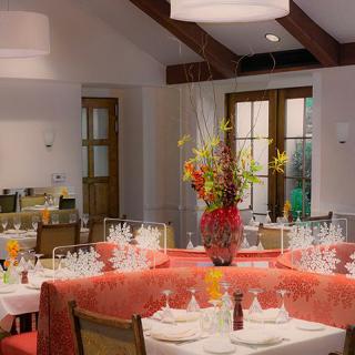 A beautifully decorated restaurant dining area with elegantly set tables and floral centerpieces.