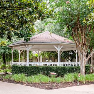 A charming gazebo surrounded by lush greenery in a peaceful park setting.
