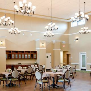 A spacious dining area with elegant chandeliers and neatly arranged tables and chairs.
