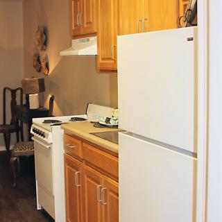 A compact kitchen with wooden cabinets, a refrigerator, and a stove.