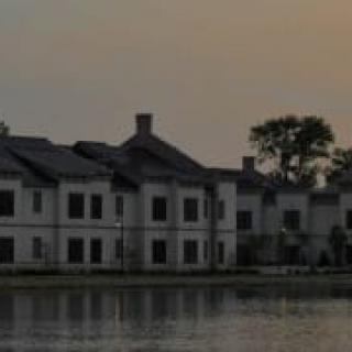A row of houses by the lake at dusk, with their reflections shimmering on the water.