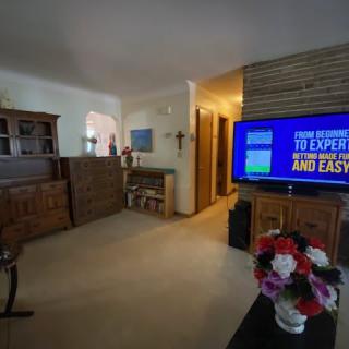 A cozy living room featuring a television, wooden furniture, and decorative flowers.