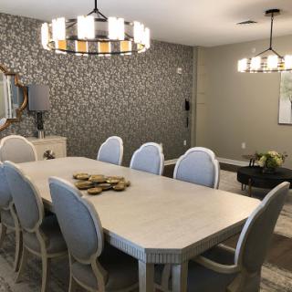 A modern dining room featuring a large table with elegant chairs and stylish lighting fixtures.