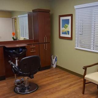 A cozy salon interior featuring a barber chair, mirror, and wooden furniture.