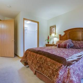 A cozy bedroom with a large bed, decorative pillows, and a wooden headboard.