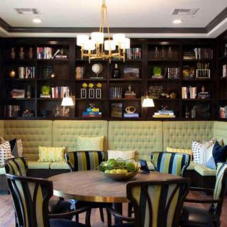 A cozy living room with a built-in bookshelf, elegant seating, and a central chandelier.