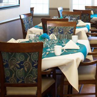 A cozy dining area setup with elegantly arranged tables, adorned with patterned chairs and glassware.