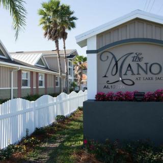A residential housing area with a decorative entrance sign and palm trees in the background.