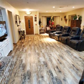 A cozy living room with hardwood floors, reclining chairs, and warm lighting.