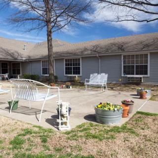 A backyard patio area with outdoor furniture and potted plants in front of a house.