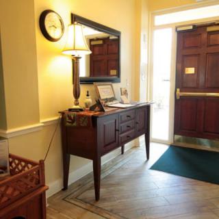 A cozy entryway featuring a wooden sideboard, a lamp, and a mirror.
