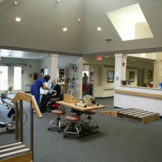 A rehabilitation center with exercise equipment and healthcare professionals assisting patients.