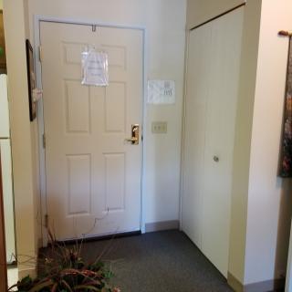 An interior view of an apartment entrance with a door, hallway, and notice posted on the door.