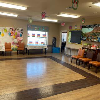 A spacious community room featuring a wooden floor and seating arranged for events.