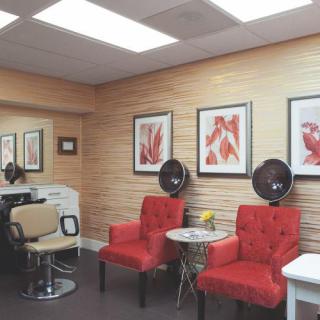 A cozy salon interior featuring red chairs, wall art, and hair dryers.