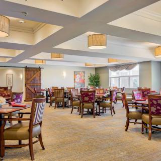 Spacious dining area with neatly arranged tables and chairs, featuring warm lighting and elegant decor.