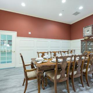 A stylish dining room with a large wooden table and chairs, set against red walls with white wainscoting.