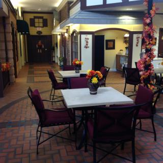 A cozy indoor restaurant setting with decorated tables and chairs, illuminated by warm lighting.
