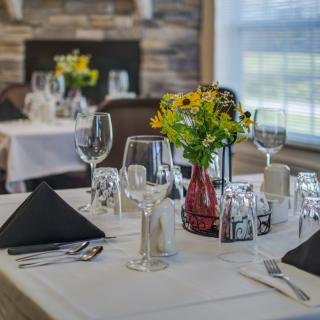 A beautifully set table in a fine dining restaurant with flowers and elegant glassware.