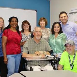 A cheerful group of people posing together in an office setting.
