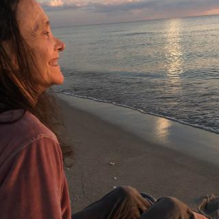 A woman enjoys a peaceful sunset by the ocean.