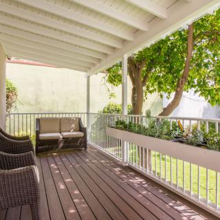 A cozy outdoor deck with seating overlooking a lush garden.