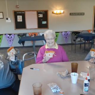 A group of elderly people enjoying a crafts activity in a decorated room.
