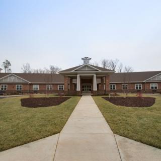 A symmetrical brick building with a central entrance and landscaped pathway.