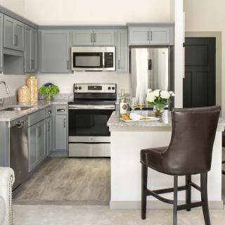 A modern kitchen with gray cabinets and stainless steel appliances.