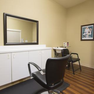 A tidy hair salon interior featuring a chair, mirror, and workspace.